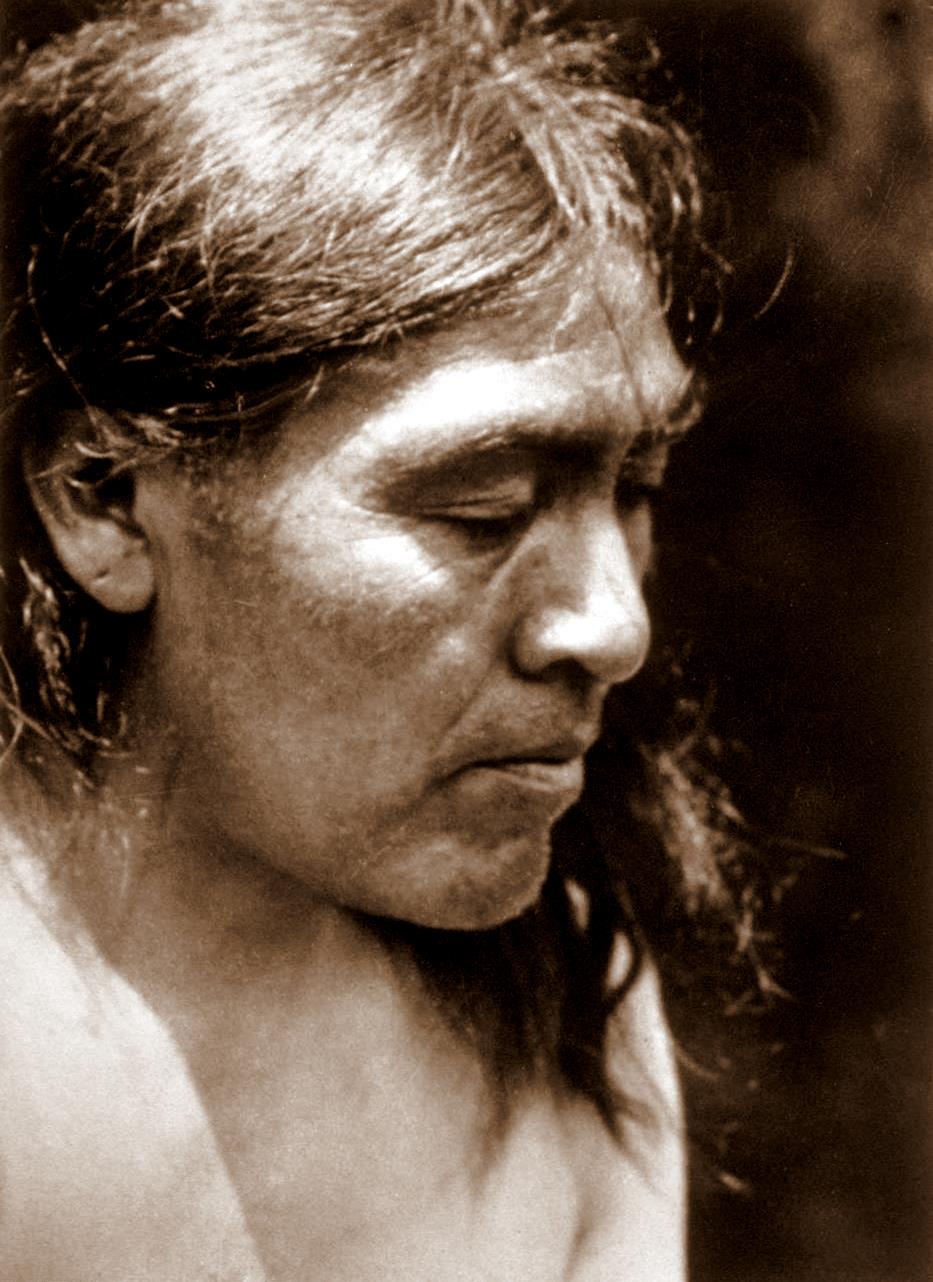 Retrato fotográfico de estudio, de perfil y con enfoque suave, de Ishi con el pelo corto y el hombro descubierto