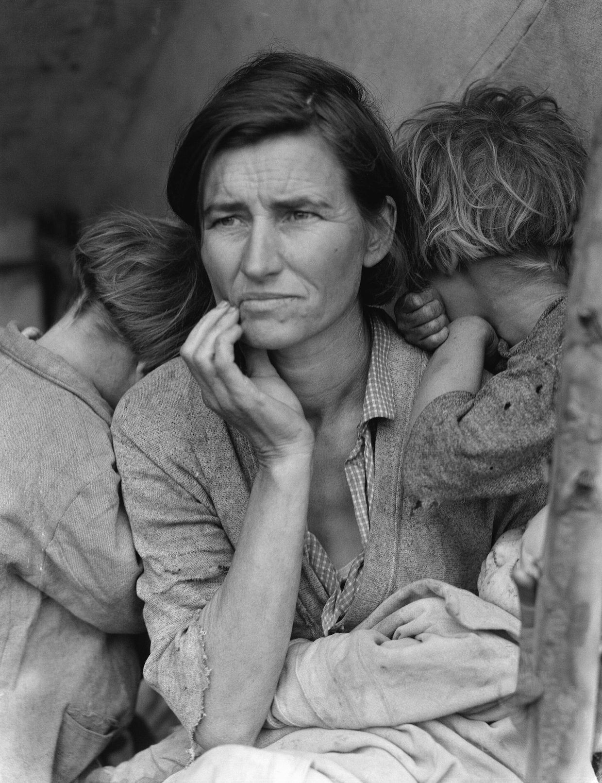 Fotografía de 1936 de una mujer con expresión preocupada sosteniendo a un bebé, con dos niños apoyados en sus hombros y la cara vuelta